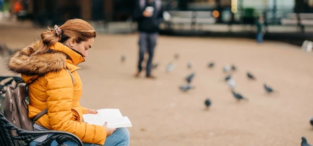 Woman reading a book on a park bench